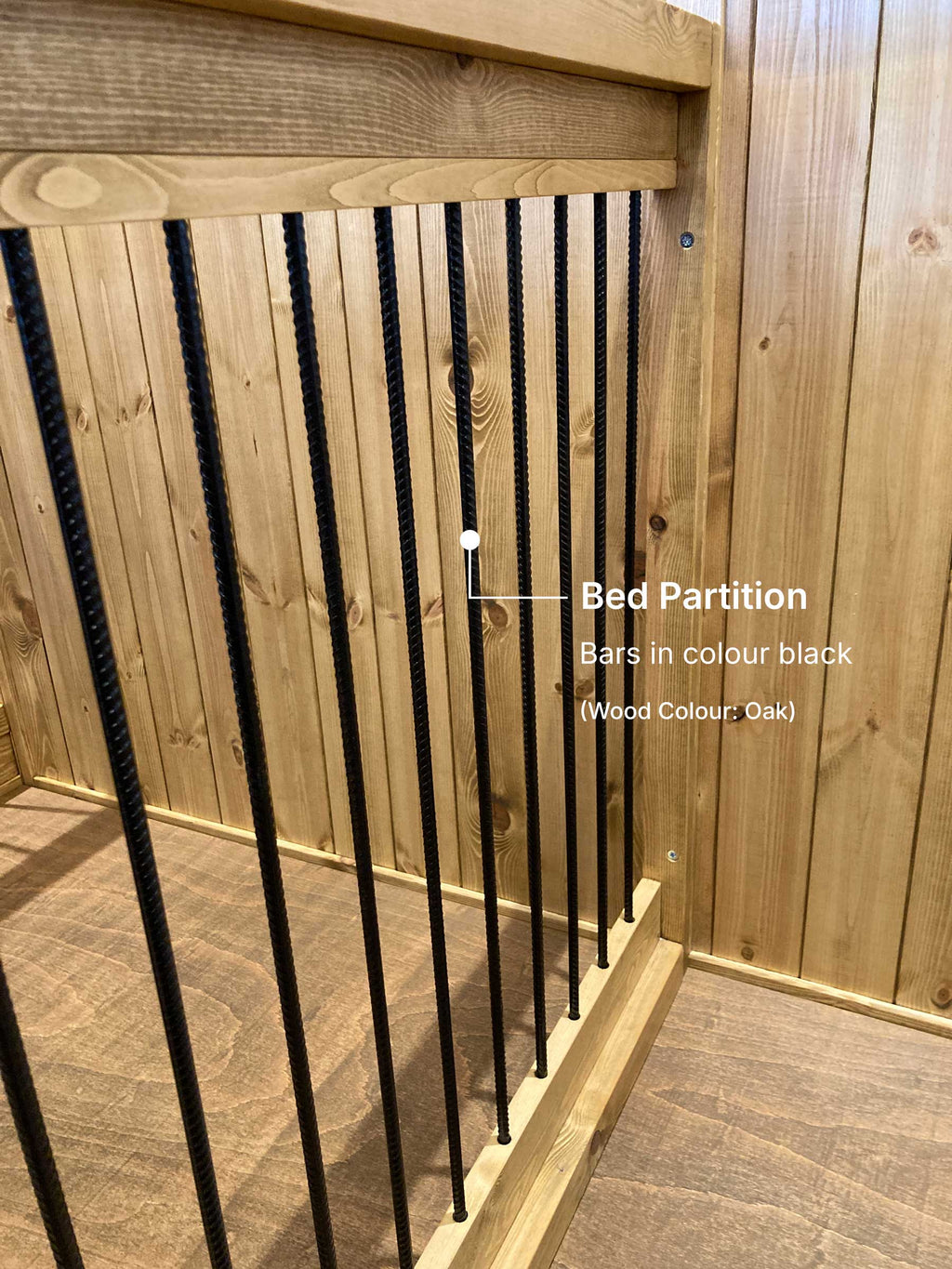 Close-up of oak double wooden dog crate showing black bar bed partition separating the two sleeping areas.