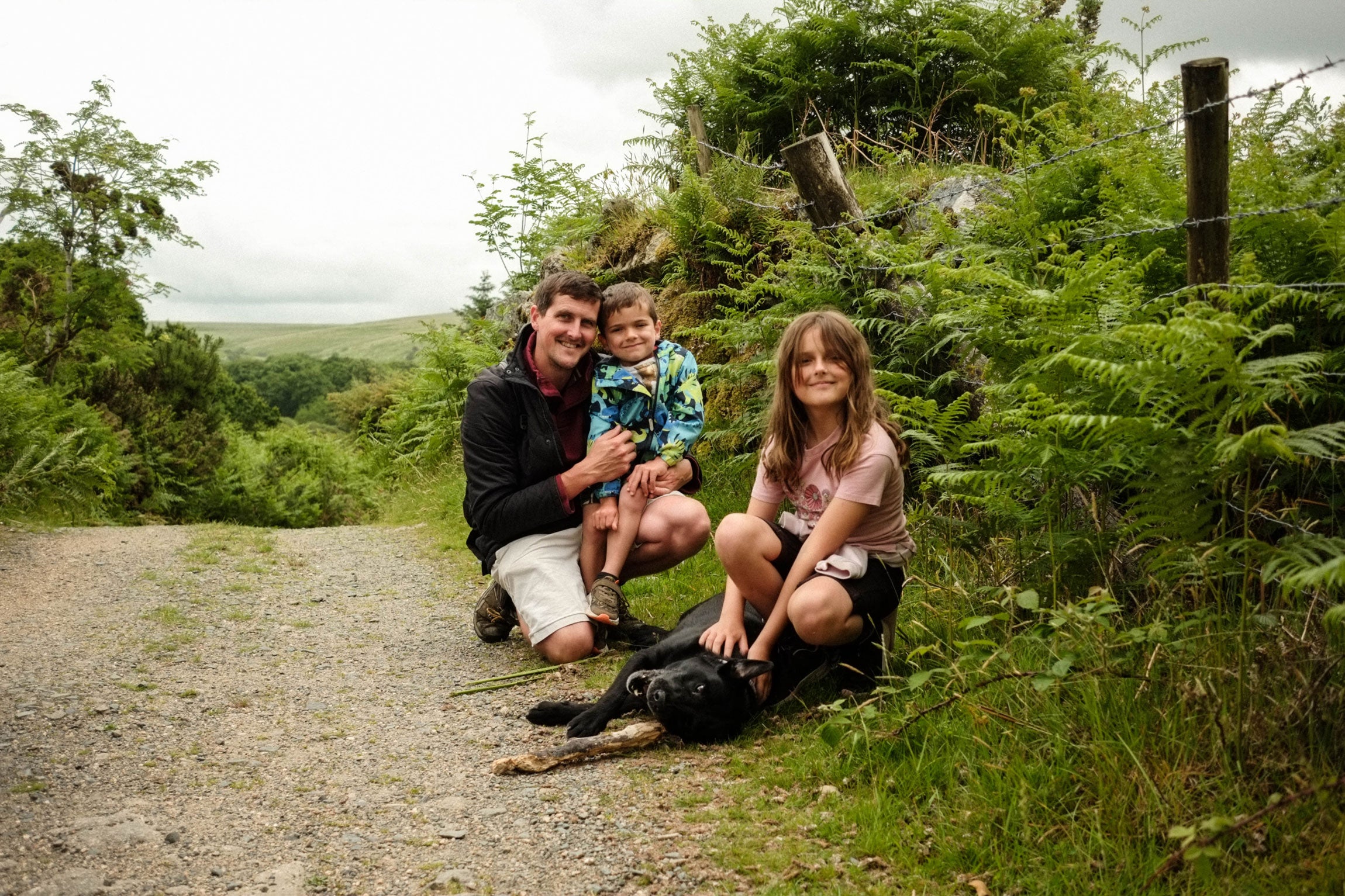Family with two children and a dog on Dartmoor sitting on a path surrounded by greenery