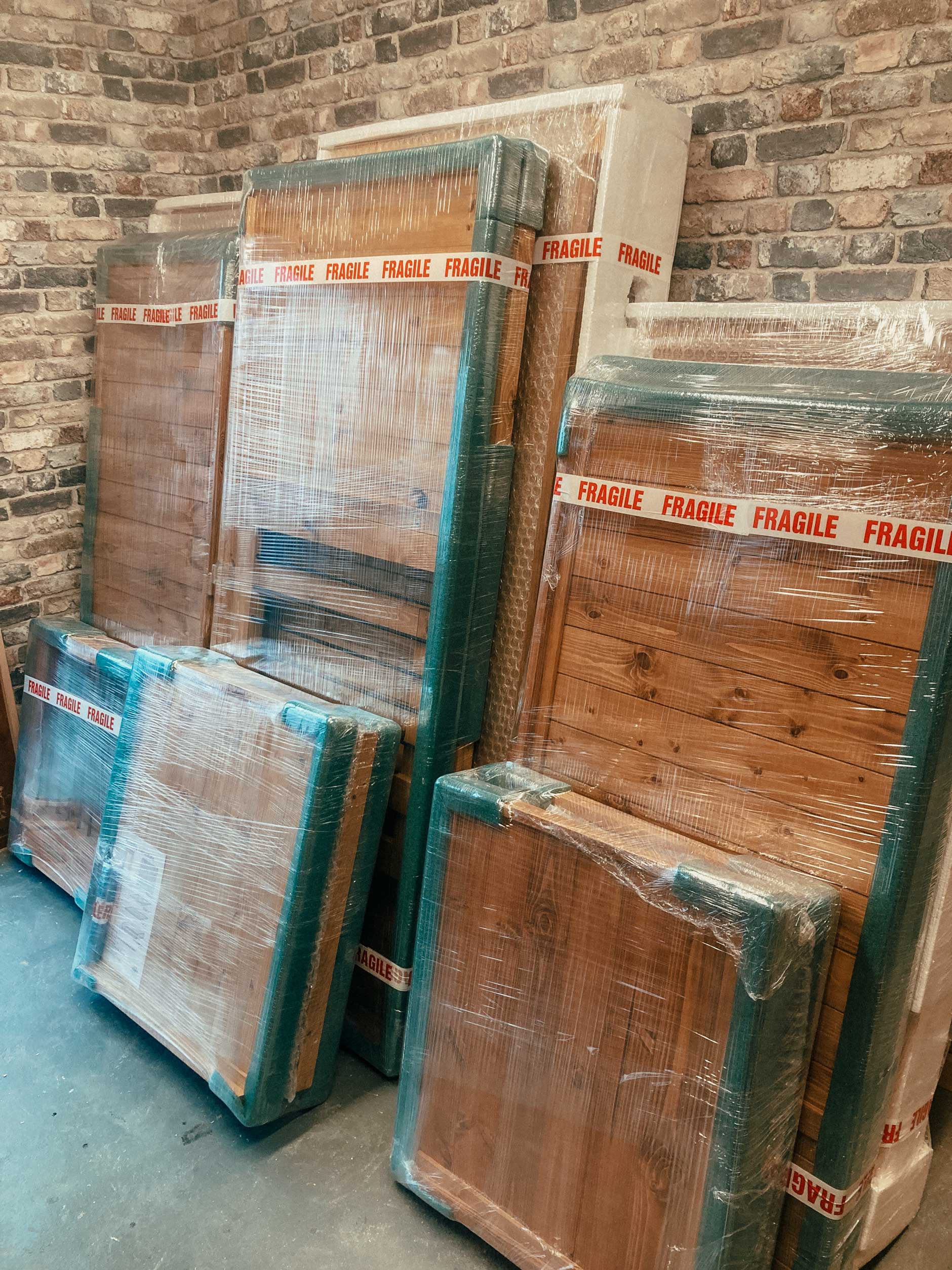 Flat-packed wooden dog crate furniture wrapped securely for delivery, showing protective packaging for handcrafted wooden dog crates.