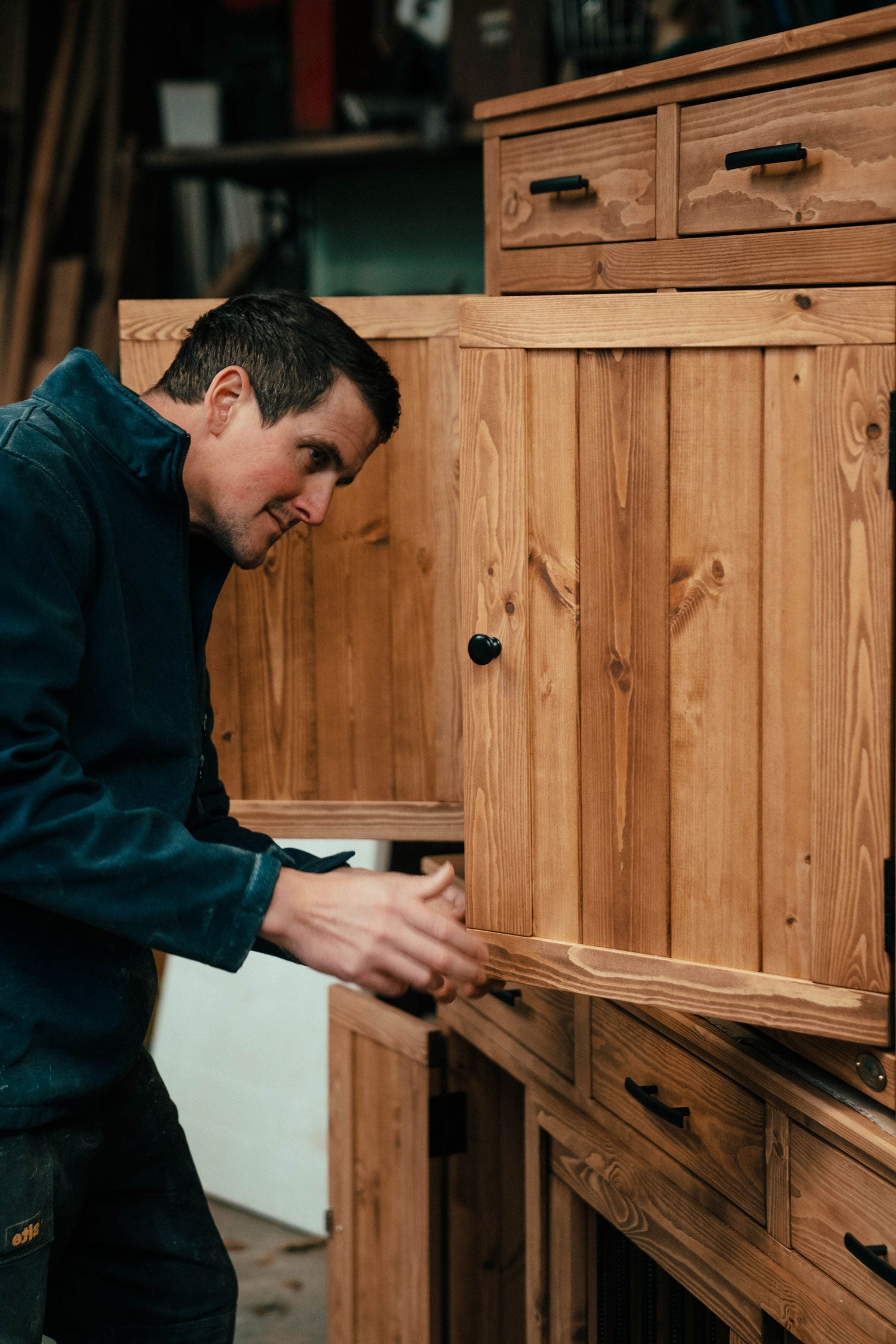 Craftsman assembling handcrafted wooden dog crate furniture in workshop, showing premium solid timber construction and bespoke detailing.