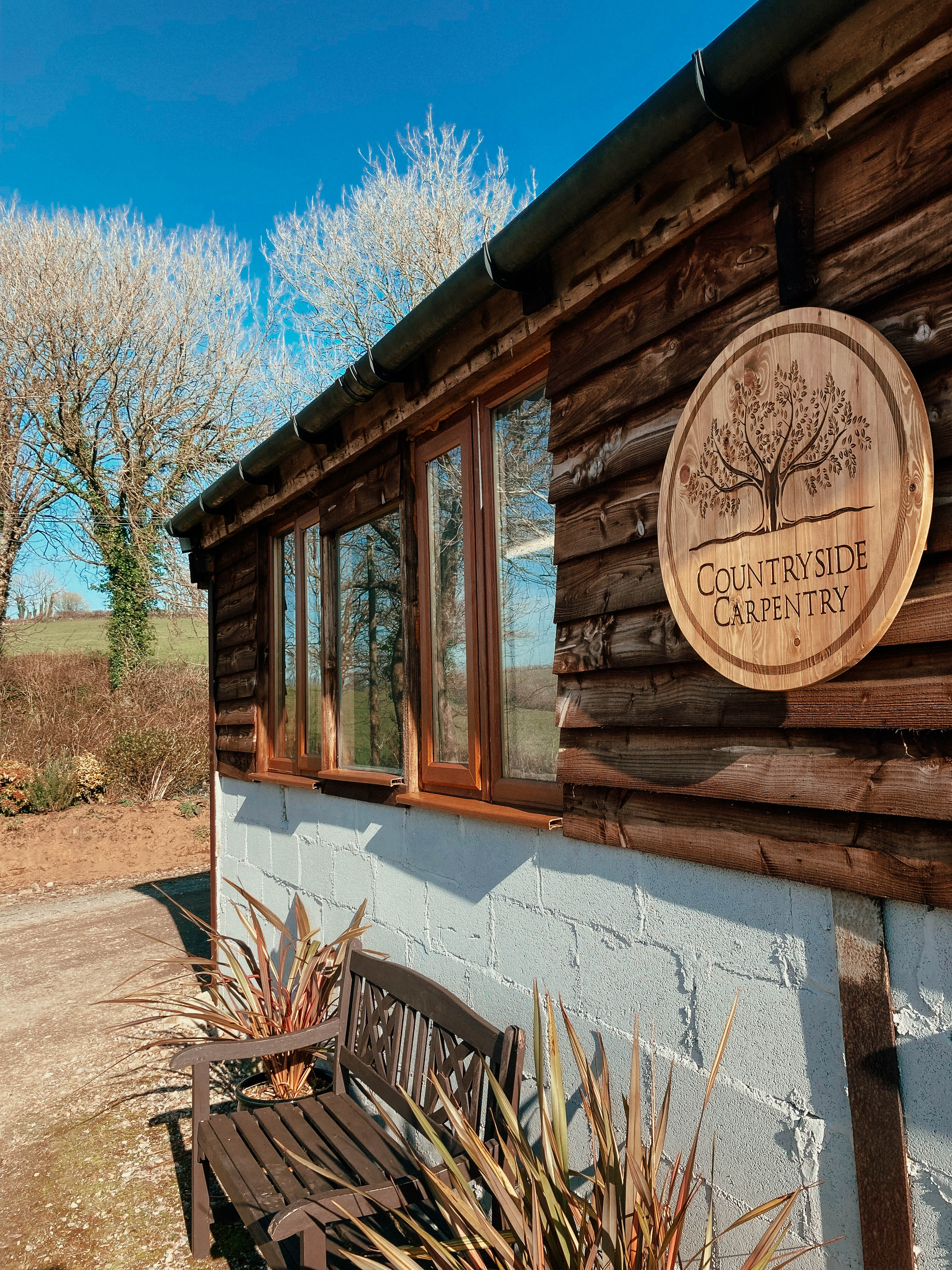 Workshop exterior with wooden cladding and Countryside Carpentry sign — showcasing the Devon workshop where handcrafted wooden dog crate furniture is made.